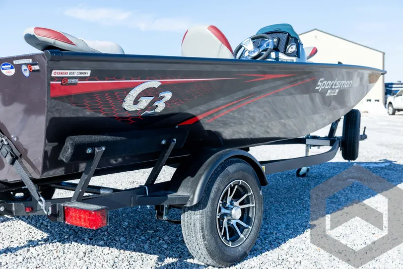 Slide: The Image of 2025 G3 Sportsman 1610 boat on trailer, black with red accents, parked on gravel. - 16