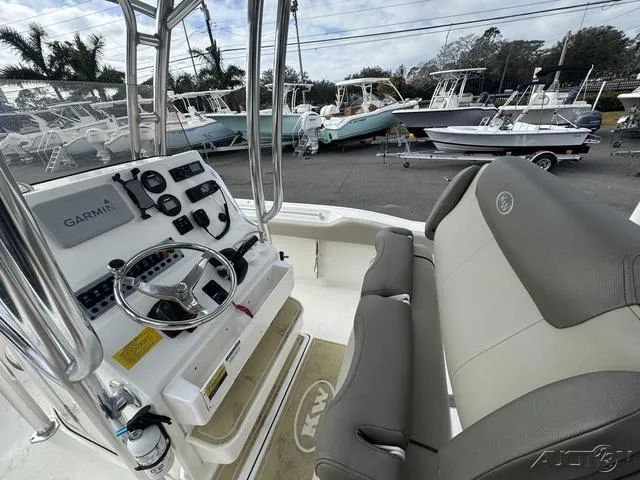 Slide: The Image of 2021 Key West 219fs boat interior with steering console and seating, parked among other boats. - 27