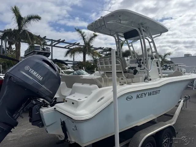 Slide: The Image of 2021 Key West 219fs boat with Yamaha engine, parked on a trailer, surrounded by palm trees. - 3