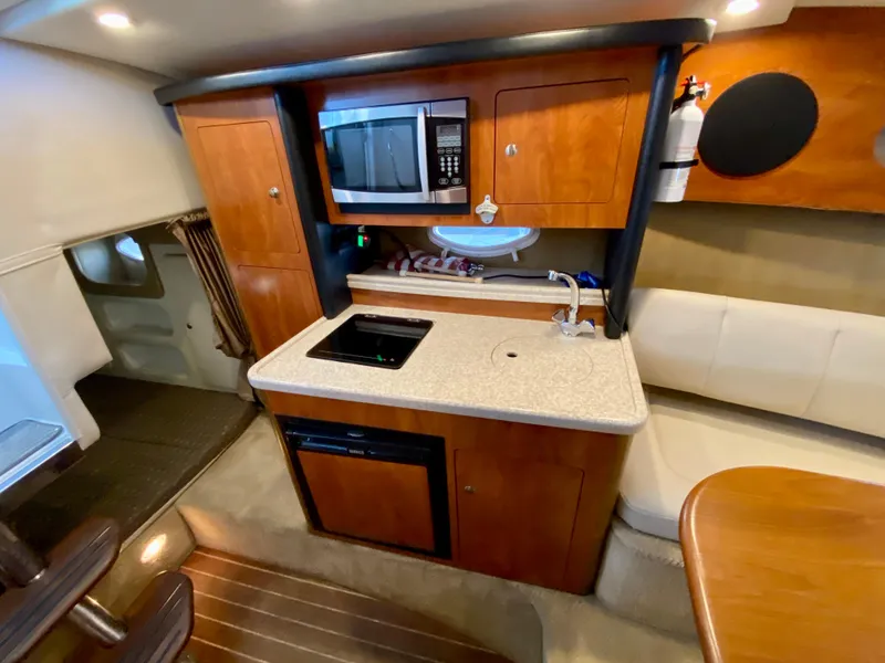 Slide: The Image of 2008 Rinker 280 Express Cruiser interior with kitchenette, microwave, and seating area. - 12