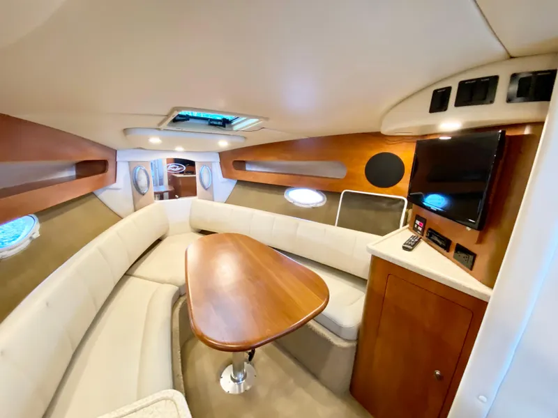 Slide: The Image of 2008 Rinker 280 Express Cruiser interior with seating, table, and TV. - 13