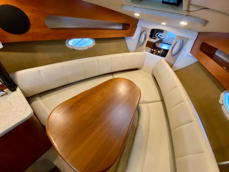 Slide: The Image of 2008 Rinker 280 Express Cruiser interior with white seating and wooden table. - 14