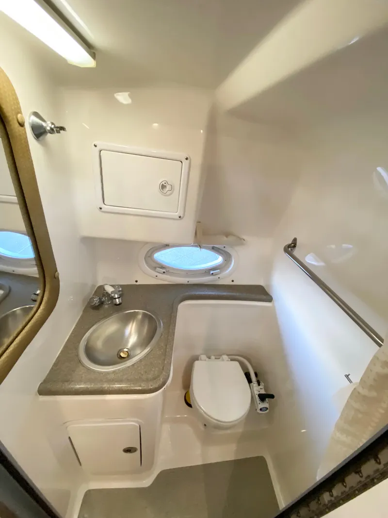 Slide: The Image of 2008 Rinker 280 Express Cruiser bathroom with sink, toilet, and porthole window. - 21