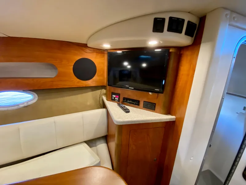 Slide: The Image of 2008 Rinker 280 Express Cruiser interior with TV, wood paneling, and seating area. - 22