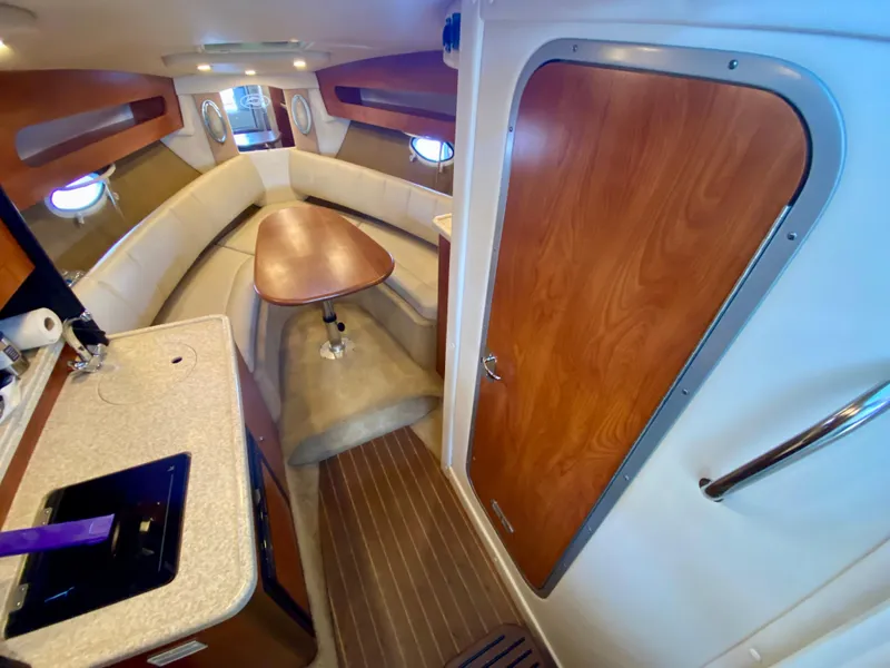 Slide: The Image of 2008 Rinker 280 Express Cruiser interior with kitchenette, seating, and wooden accents. - 48