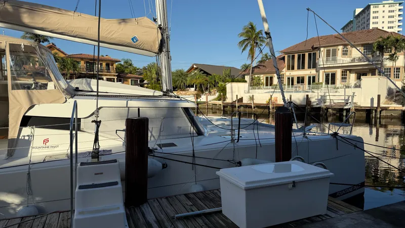 Slide: The Image of 2024 Fountaine Pajot Catamaran Elba 45 docked near waterfront homes. - 2