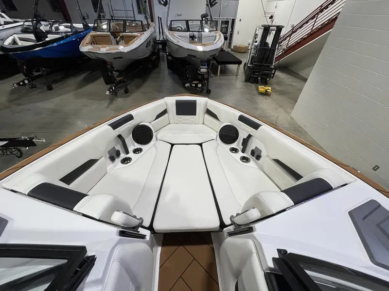 Slide: The Image of 2025 Malibu 26 LSV boat interior with white seating and speakers in showroom. - 19