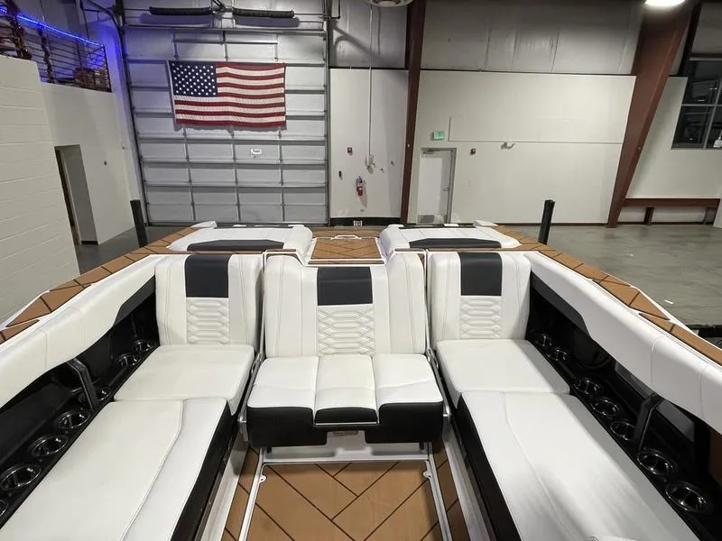Slide: The Image of 2025 Malibu 26 LSV boat interior with white seating in a garage setting. - 23