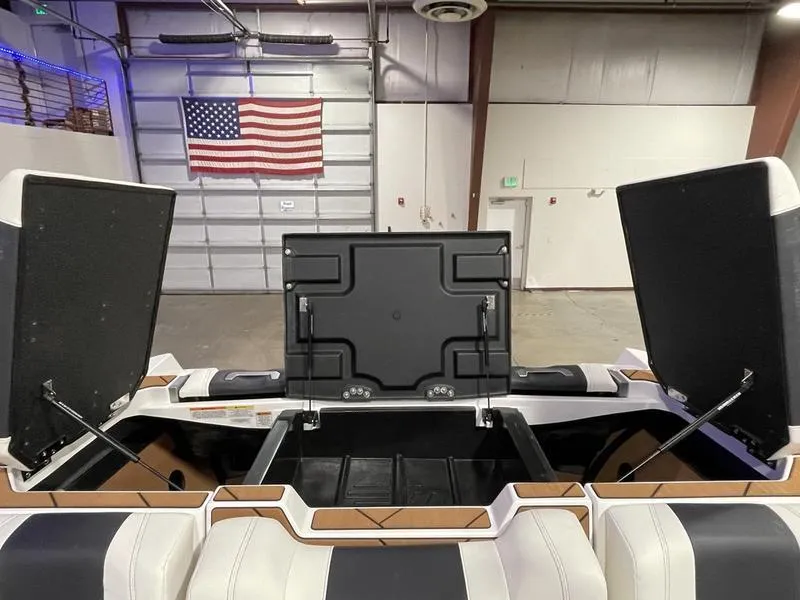 Slide: The Image of 2025 Malibu 26 LSV boat interior with open storage compartments, American flag in background. - 30