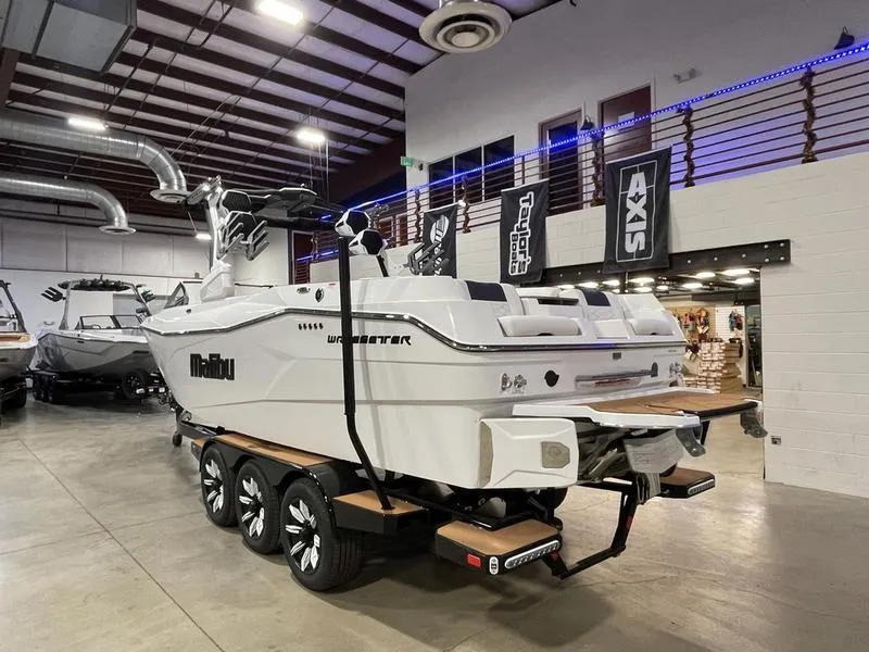 Slide: The Image of 2025 Malibu 26 LSV boat displayed indoors on a trailer. - 8