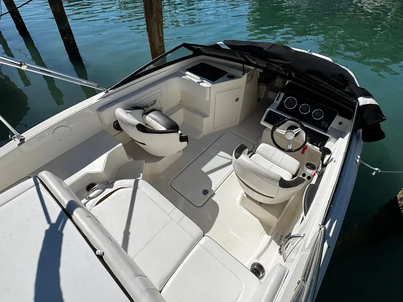 Slide: The Image of 2019 Sea Ray SPX 190 OB boat interior with seating and steering wheel, docked on calm water. - 14