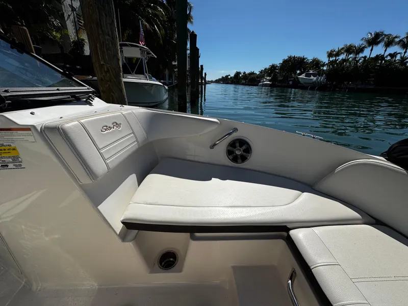 Slide: The Image of 2019 Sea Ray SPX 190 OB boat interior with white seating by a scenic waterway. - 20