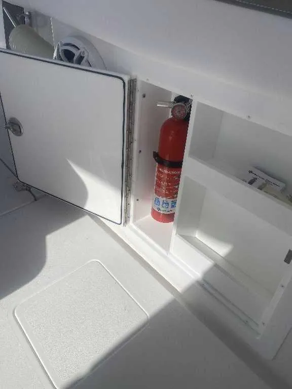Slide: The Image of Open storage compartment on 2025 Caymas 34 CT boat with fire extinguisher inside. - 23