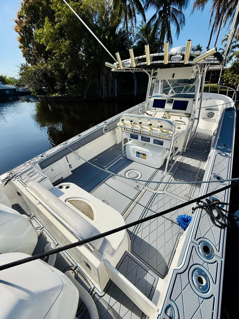 Slide: The Image of 2003 Fountain 38 TE boat with spacious deck, docked near lush greenery. - 11