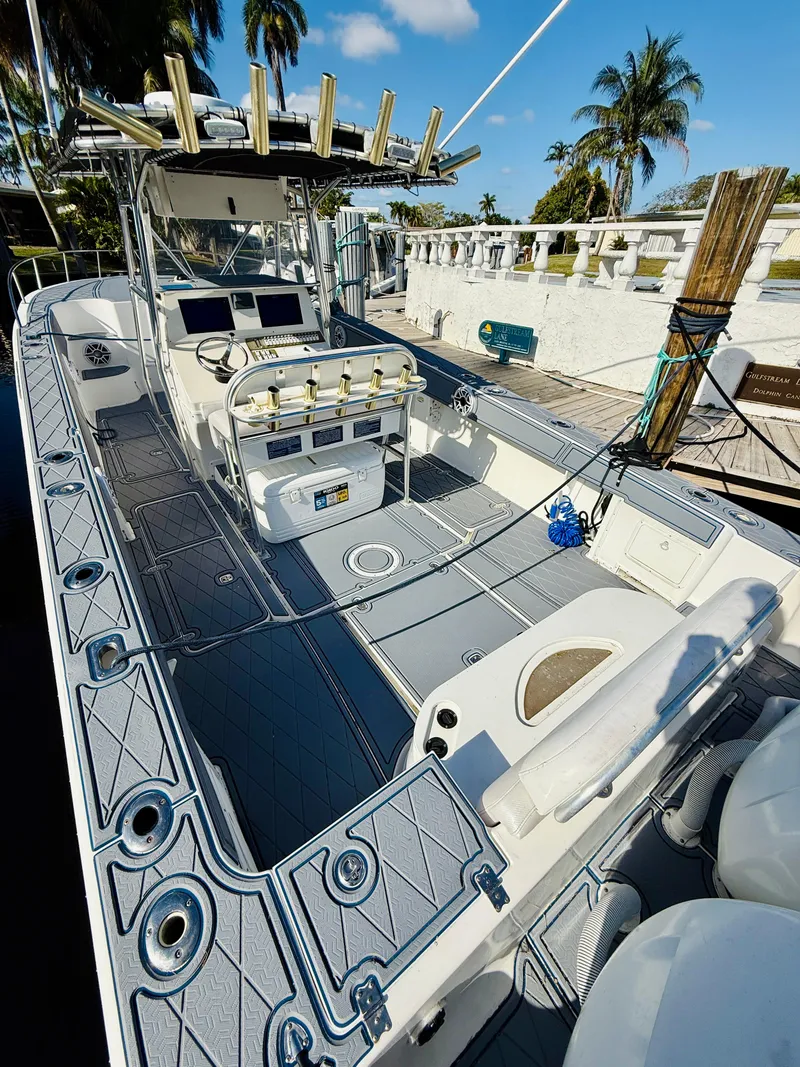Slide: The Image of 2003 Fountain 38 TE boat with spacious deck and fishing equipment, docked under clear skies. - 12