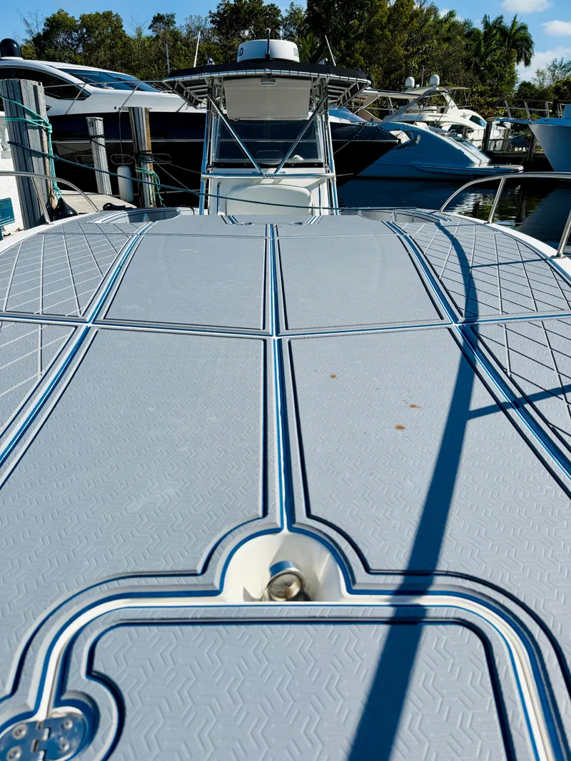 Slide: The Image of 2003 Fountain 38 TE boat docked, showcasing sleek deck design and nearby yachts. - 3
