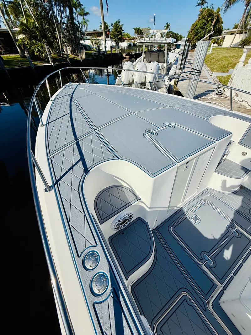 Slide: The Image of 2003 Fountain 38 TE boat with sleek deck design, docked near lush greenery. - 7