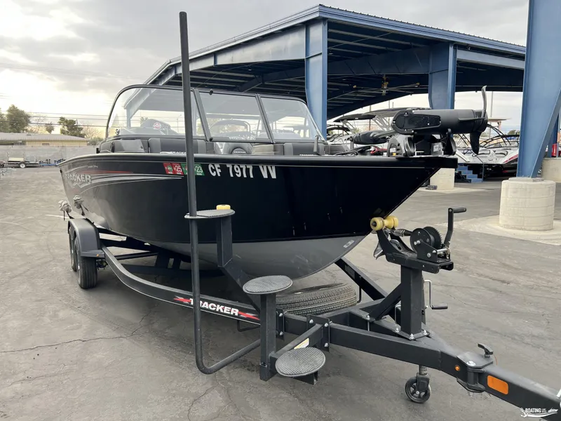 Slide: The Image of 2023 Tracker V-19 boat on trailer, parked outdoors near a blue structure. - 11