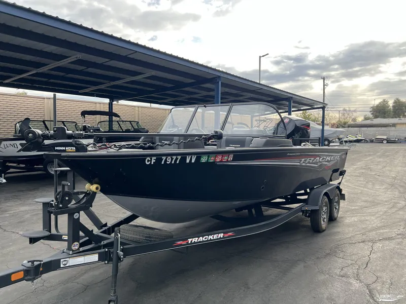 Slide: The Image of 2023 Tracker V-19 boat on trailer, parked under a canopy in a lot. - 2