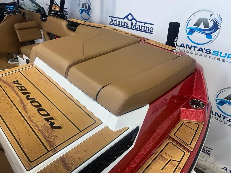 Slide: The Image of 2025 Moomba Max boat interior with tan seating and wood accents at Atlanta Marine showroom. - 12