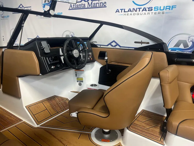 Slide: The Image of 2025 Moomba Max boat interior with tan seating and modern dashboard at Atlanta Marine showroom. - 19