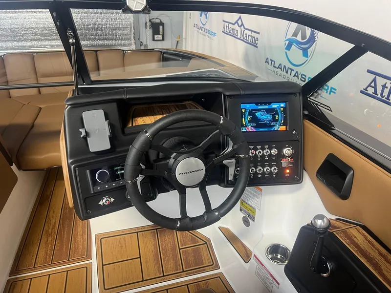 Slide: The Image of 2025 Moomba Max boat interior with steering wheel, control panel, and wood accents. - 20
