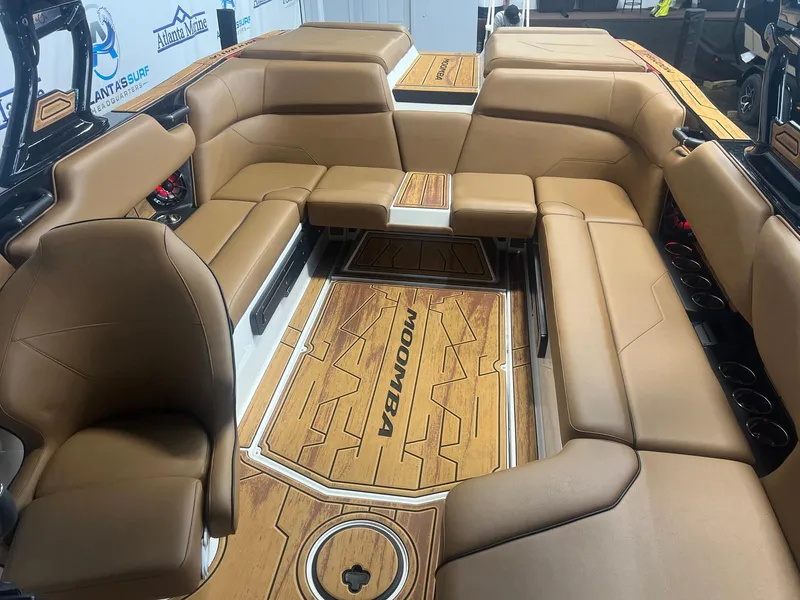 Slide: The Image of 2025 Moomba Max boat interior with tan leather seating and wood-patterned flooring. - 23