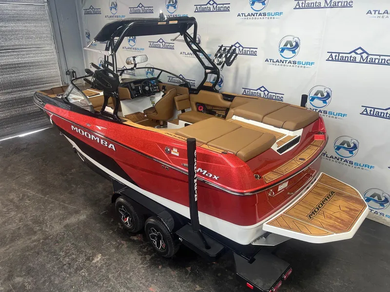 Slide: The Image of 2025 Moomba Max boat in showroom, red and white design, brown seating, Atlanta Marine backdrop. - 7
