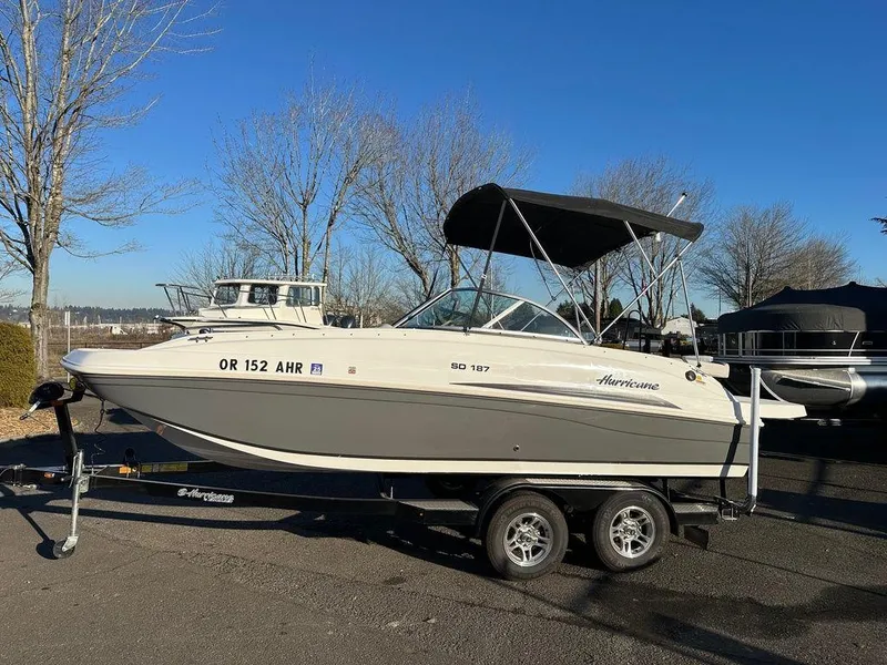 Slide: The Image of 2022 Hurricane SunDeck 187 IO boat on trailer, parked outdoors under clear blue sky. - 11