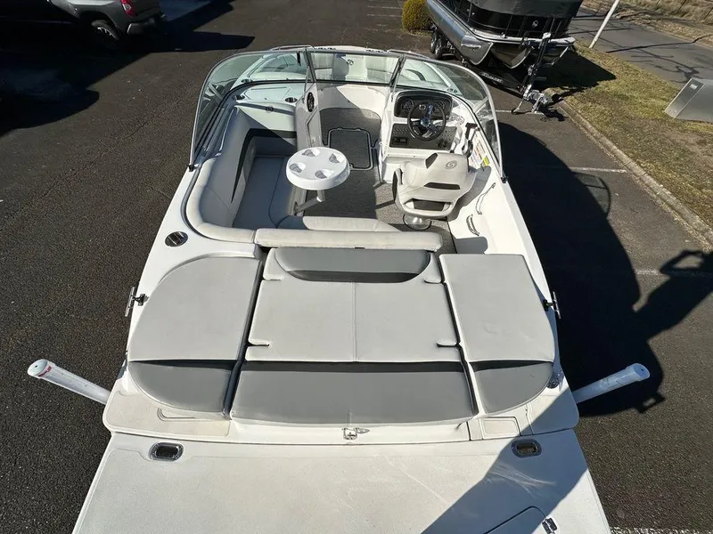 Slide: The Image of 2022 Hurricane SunDeck 187 IO boat interior with seating and steering wheel, parked on pavement. - 2