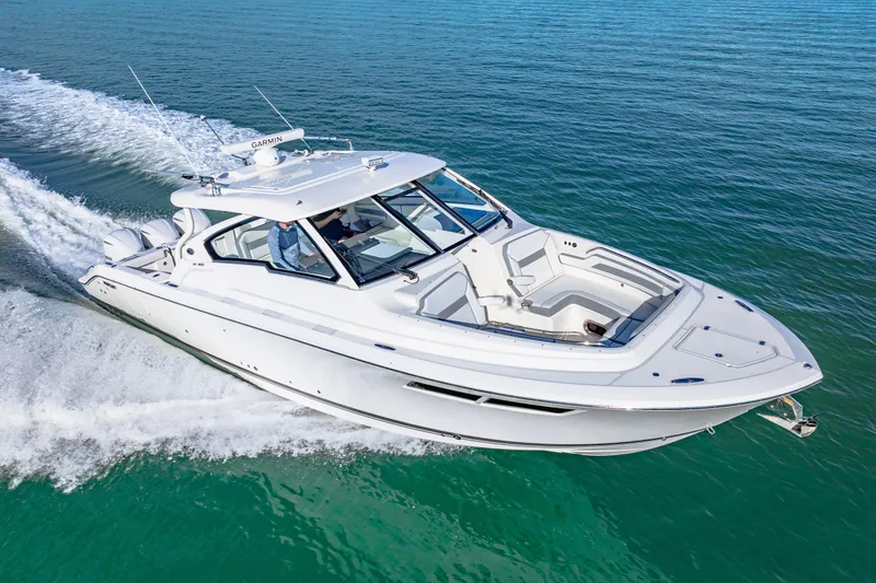 Slide: The Image of 2021 Pursuit DC 365 Dual Console boat cruising on clear blue water. - 12