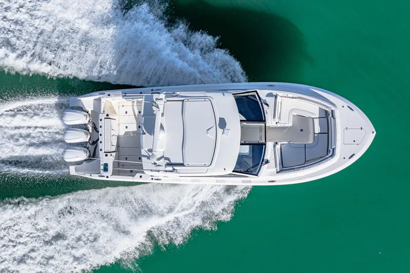Slide: The Image of 2021 Pursuit DC 365 Dual Console boat cruising on turquoise water, aerial view. - 14