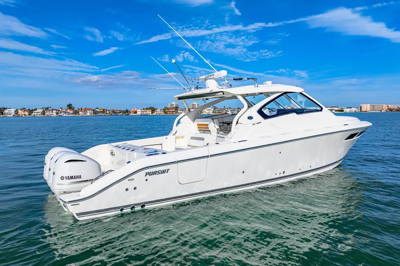 Slide: The Image of 2021 Pursuit DC 365 Dual Console boat on calm water under blue sky. - 2