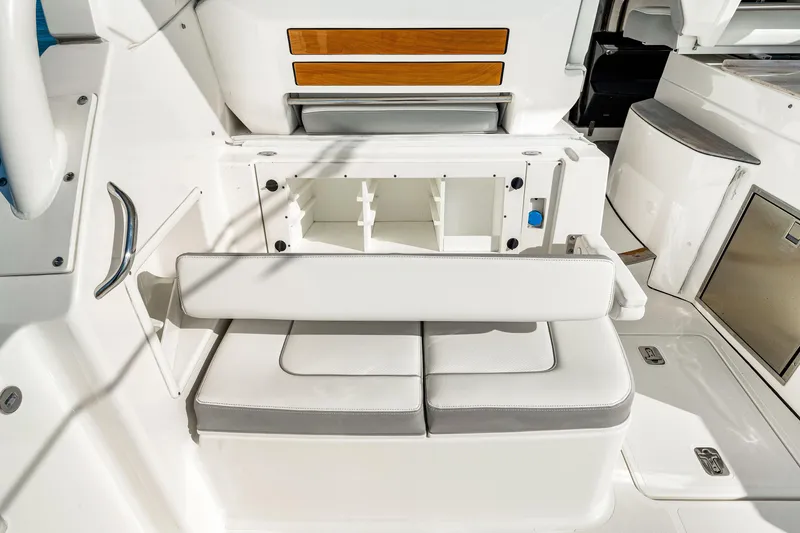 Slide: The Image of 2021 Pursuit DC 365 Dual Console boat interior with white seating and storage compartment. - 28