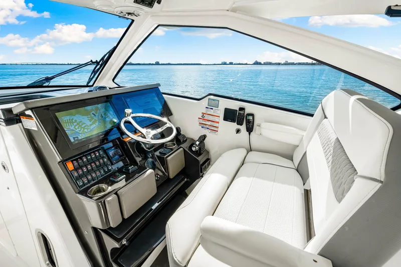 Slide: The Image of 2021 Pursuit DC 365 Dual Console interior with modern helm and seating, overlooking serene waters. - 36