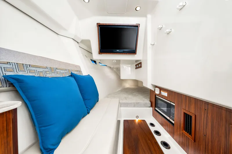 Slide: The Image of 2021 Pursuit DC 365 Dual Console interior with TV, blue cushions, and wood accents. - 47