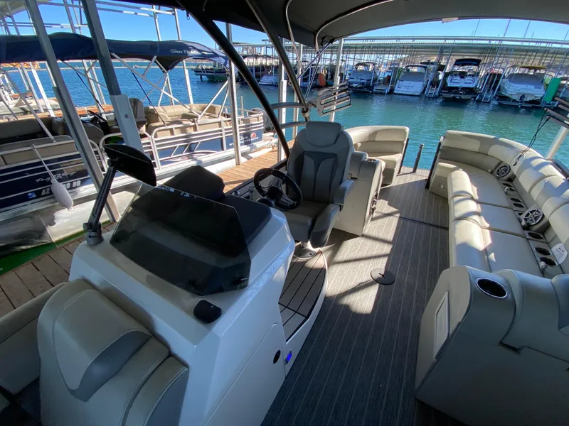 Slide: The Image of 2022 Montara 25 SURF BOSS 2.0 boat interior with seating and helm, docked at marina. - 2