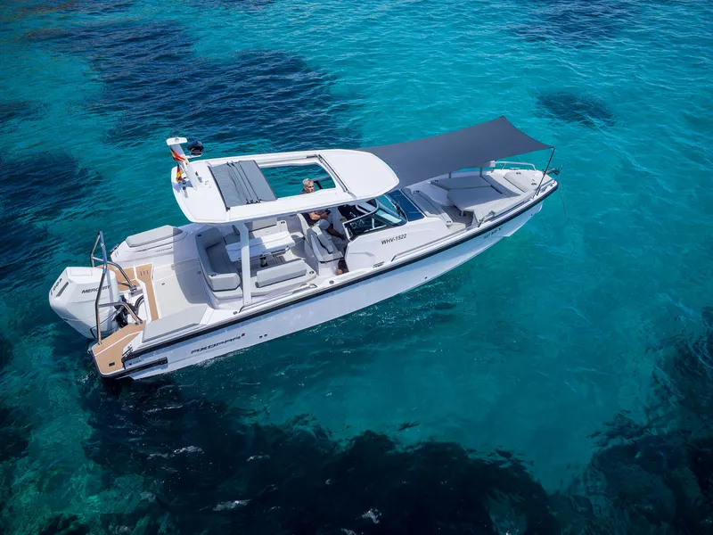 Slide: The Image of 2025 Axopar 29 Suntop boat on clear blue water, featuring sleek design and sunshade. - 1