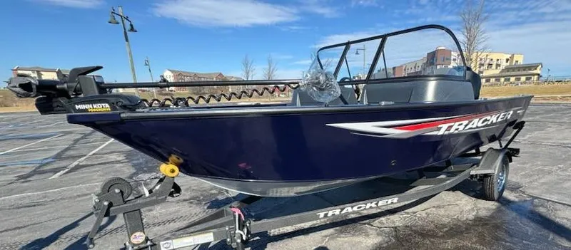 Slide: The Image of 2025 Tracker Pro Guide V-16 WT boat on trailer, parked outdoors under clear sky. - 2
