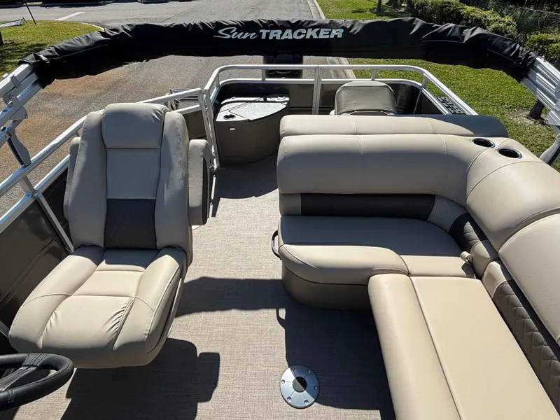 Slide: The Image of 2025 Sun Tracker Fishin' Barge 20 DLX interior with beige seating and steering wheel. - 4