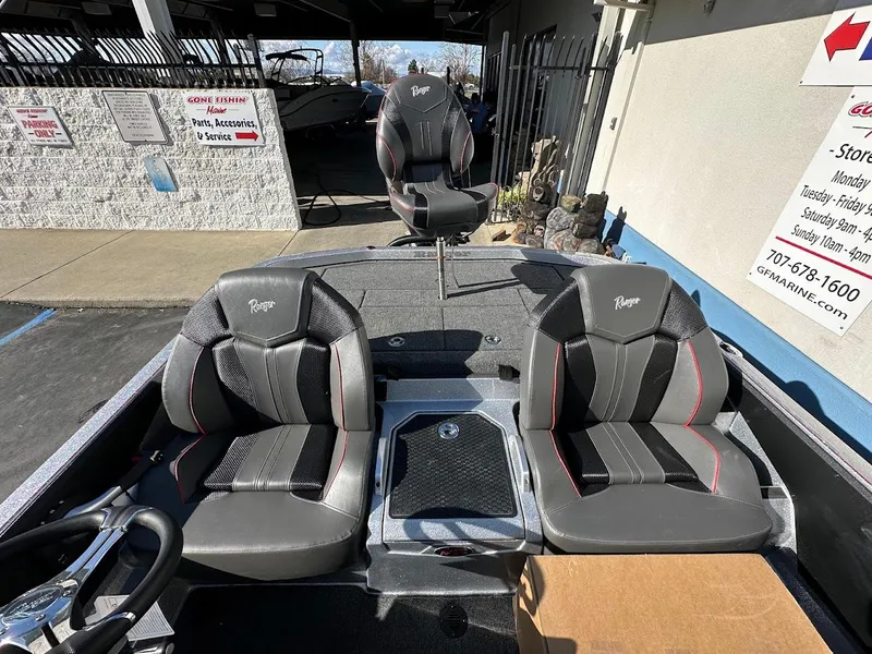 Slide: The Image of 2025 Ranger Z520 boat interior with three black and gray seats, parked at a dealership. - 16