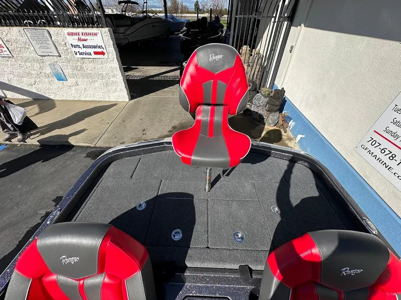 Slide: The Image of 2025 Ranger Z521 boat interior with red and black seats, parked in a lot. - 17
