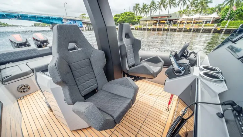Slide: The Image of 2025 Skipper 38 NC boat interior with modern seating and controls, docked by a scenic waterfront. - 14