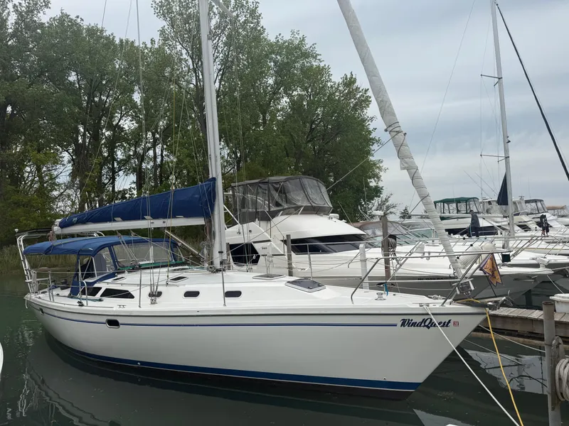 Slide: The Image of 2001 Catalina 42 MkII sailboat docked in a marina, surrounded by trees and other boats. - 0
