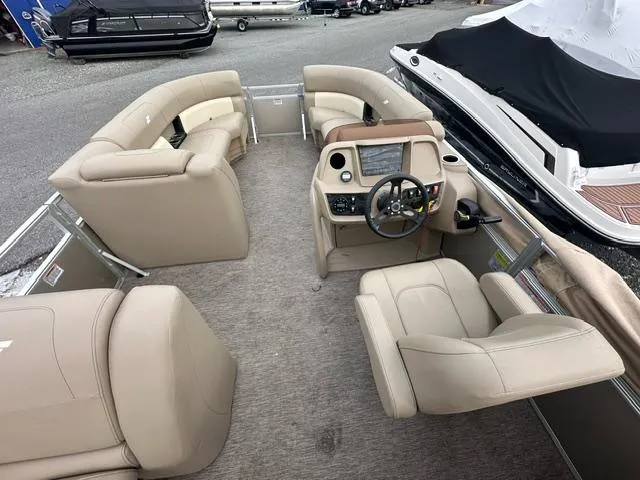 Slide: The Image of 2021 Starcraft LX 22 R pontoon boat interior with beige seating and steering console. - 3