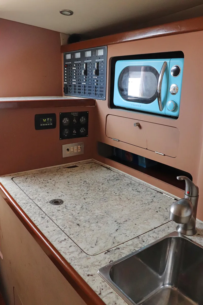Slide: The Image of 1997 Gamefisherman 34 Express boat interior with kitchenette, featuring a microwave and sink. - 29