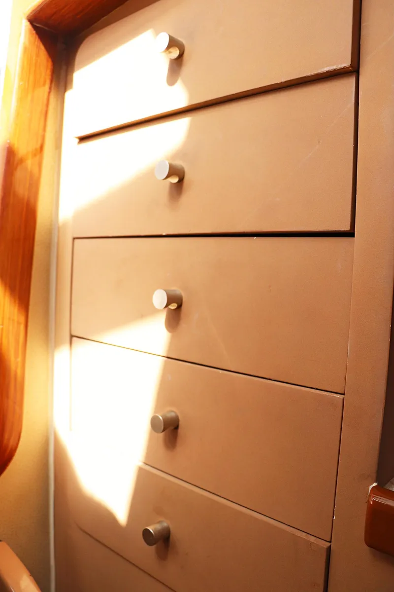 Slide: The Image of Wooden drawers inside a 1997 Gamefisherman 34 Express boat, illuminated by sunlight. - 45