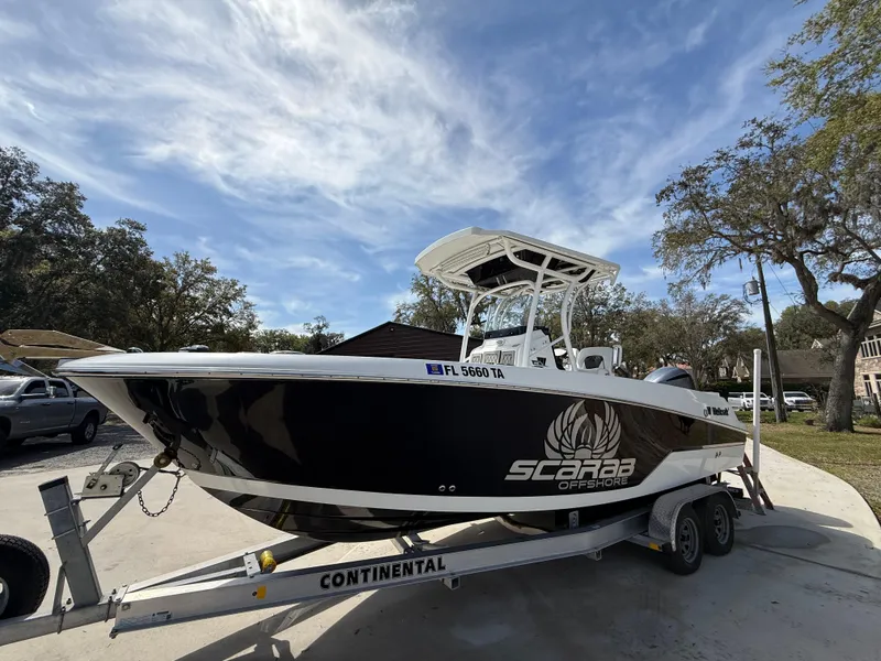 Slide: The Image of 2021 Wellcraft 242 Offshore boat on trailer, black hull, parked outdoors. - 0