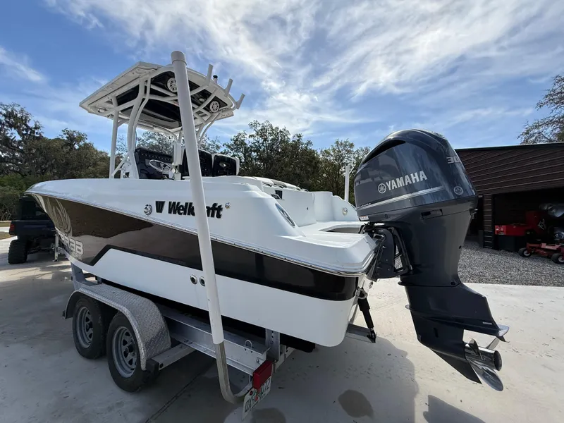 Slide: The Image of 2021 Wellcraft 242 Offshore boat with Yamaha engine on trailer, parked outdoors. - 2