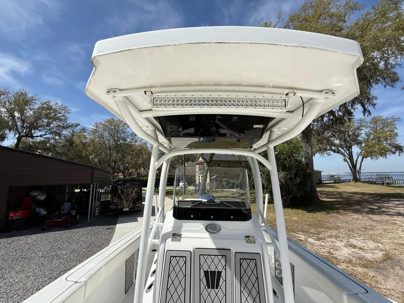 Slide: The Image of 2021 Wellcraft 242 Offshore boat with T-top, parked outdoors under a clear sky. - 42